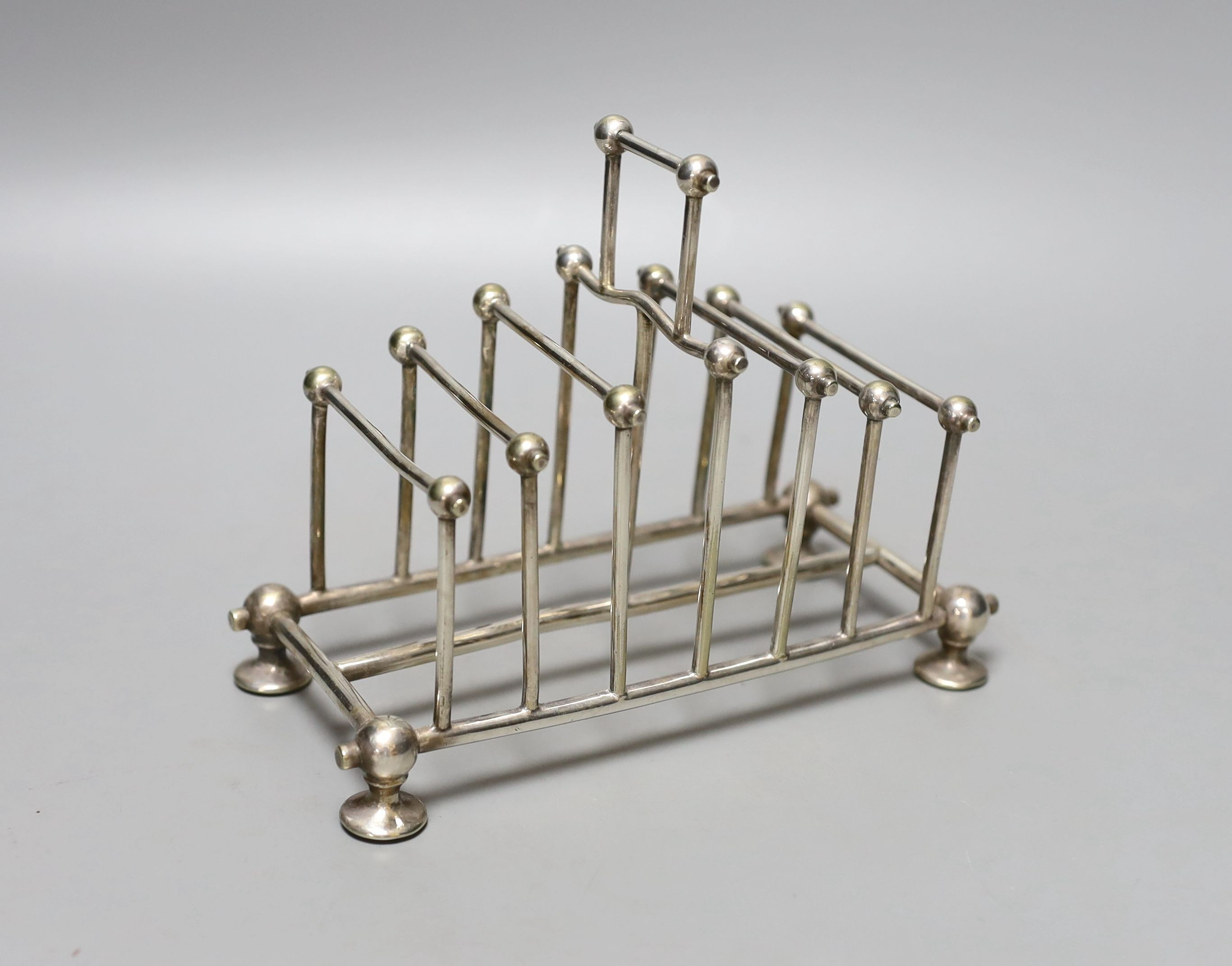 A late Victorian silver plated graduated seven bar toastrack, in the manner of Christopher Dresser, by William Hutton & Sons, length 16.4cm.